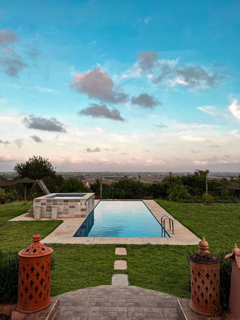 Piscina rodeada de césped con vistas al campo.
